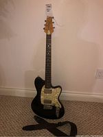 Full front view of guitar leaning against wall with strap attached