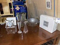 Wide view of Mikasa crystal items including bowl, vase, two candle holders, and table clock on wooden table with original Mikasa box