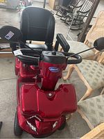 Front-on view showing red body, front headlights, tiller and seat