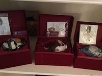 Three hand-painted glass ornaments in individual red velvet boxes, each with accompanying certificate of authenticity and informational card. Ornaments feature artistic and musical themed designs.