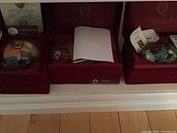 Three hand painted glass hanging bulbs placed in red velvet boxes each with a certificate of authenticity, showing overall packaging and presentation.