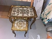 Two ornate nesting tables with decorative tops, visible scalloped edges, and curved carved legs.