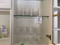 Three crystal tumblers on a glass shelf with etched pinwheel design.