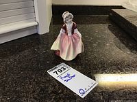 View of the Royal Doulton porcelain figurine 'Dinky Do' standing on a granite countertop, showing full figure and overall condition.