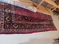 Partially unrolled rug on concrete floor next to shelving