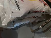 Four unopened bags of Superior Crystal water softener salt pellets stacked on a basement floor near a pipe.