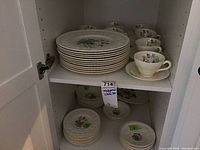 Set items stored in cabinet showing stacked dinner plates, side plates, bowls, and tea cups with saucers.
