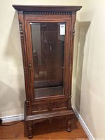 Front view of entire cabinet showing glass door, beaded trim, lower drawers and turned legs