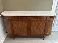 Front view of marble top buffet showing fluted central doors, curved side cabinets and tapered legs.
