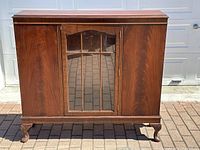 Front view of cabinet showing central mullioned glass door and two side wooden doors
