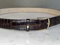 Full view of dark brown alligator skin belt with brass buckle and keeper loop.