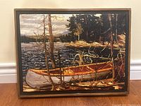 Front view of textured art print showing canoe on lake shore, framed in wood.