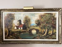 Photo showing full frontal view of the large framed oil on canvas landscape painting and built-in light on frame at top center.