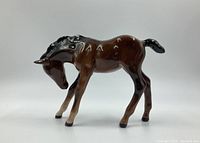 Side angle view of the glossy brown and black Beswick horse figurine showing detail of its head and bent front leg.
