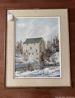 Framed oil painting showing the entire artwork including beige mat and gold-tone frame, depicting the Mill building in a winter landscape.