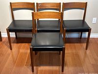 Front view of all four teak dining chairs arranged in two rows