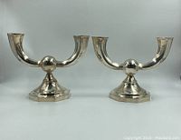 Front view of both silver candlesticks side by side showing dual-arm design and octagonal bases