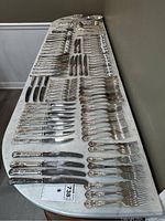 Overall view of all flatware pieces laid out on a marble-topped table