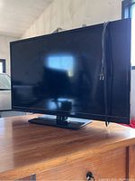 Front and side view of the 32 inch Insignia LED TV on a base stand with power cable attached.