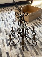 Six-arm antique brass finish chandelier with scrollwork and chain, shown hanging and inside a cardboard box.