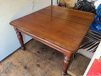 Angle view of the table top and leg intersection showing rounded top edges and wood grain.