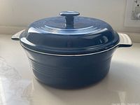 Blue crock with lid from side angle on white surface in natural light
