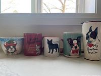 Front view of all five mugs and bowl displaying Boston Terrier and French Bulldog themed illustrations and text