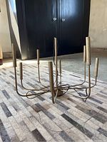 Chandelier sitting on a carpeted floor. Shows the full form with 8 candelabra arms and central support.