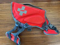 Side view of red and grey dog life jacket showcasing reflective cross patch and adjustable straps