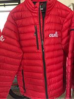 Front and left side of red puffer jacket with visible Guru logo on chest and left sleeve, zippered chest and side pockets.