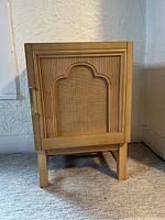 Front view of assembled brown wood nightstand with rattan inset door.