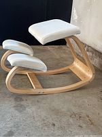 Side angle showing the ergonomic wooden frame and padded seats of the kneeling chair.