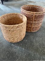 Two wicker baskets side by side on concrete floor, showing size difference.