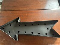 Top view showing the arrow head with circular holes on black steel material.