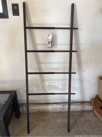Full view of Umbra Hub Ladder showing black and dark wood color with four horizontal bars