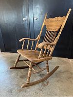 Front angled view of wooden rocking chair showing carved backrest and spindle details.