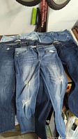 Five pairs of women's jeans in various blue denim washes and styles, laid side by side.