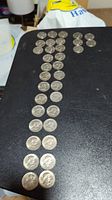 Lot of 34 Susan B. Anthony silver dollar coins laid out on a dark surface, showing multiple coins in rows.