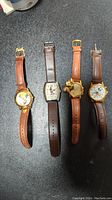 Four Disney character wristwatches laid flat showing faces and bands