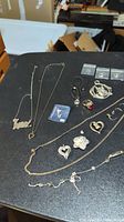 Full view of the jewelry lot laid out on black surface including necklaces, pendants, rings, earrings, and bracelets