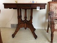 Full view of the complete antique Eastlake pedestal table showing ornate carved solid wood base and rectangular top.