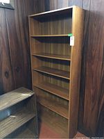 Photo of bookshelf showing full front view with five shelves and faux veneer finish.