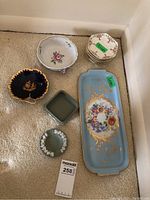 Overview of porcelain dishes, Limoges tray, Wedgwood dish and ashtray, multiple small saucers all on carpeted floor