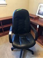 Full view of the black high back office chair showing leather seat and back design, armrests, and wheeled base.