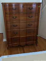 Front view of the highboy dresser showing 5 dovetailed drawers with metal handles and keyholes, and evident wood veneer finish.