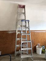 Two aluminum step ladders, showing full height comparison and condition.