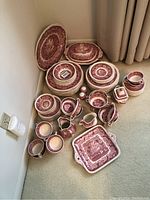 Overall view of stacked plates, bowls, cups, platters and pitchers laid on carpet.