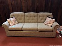 Front view of the three-seat beige multi-toned wool blend sofa with two throw pillows.