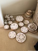 Photo showing the full set of Royal Stafford bone china dishes in Violets-Pompadour and Pompadour patterns with scalloped edges, including plates, tea cups, bowls and teapot, arranged on carpet.