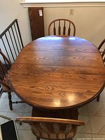 Top view of the oval wooden dining table showing the wood grain and leaf extending the table surface.